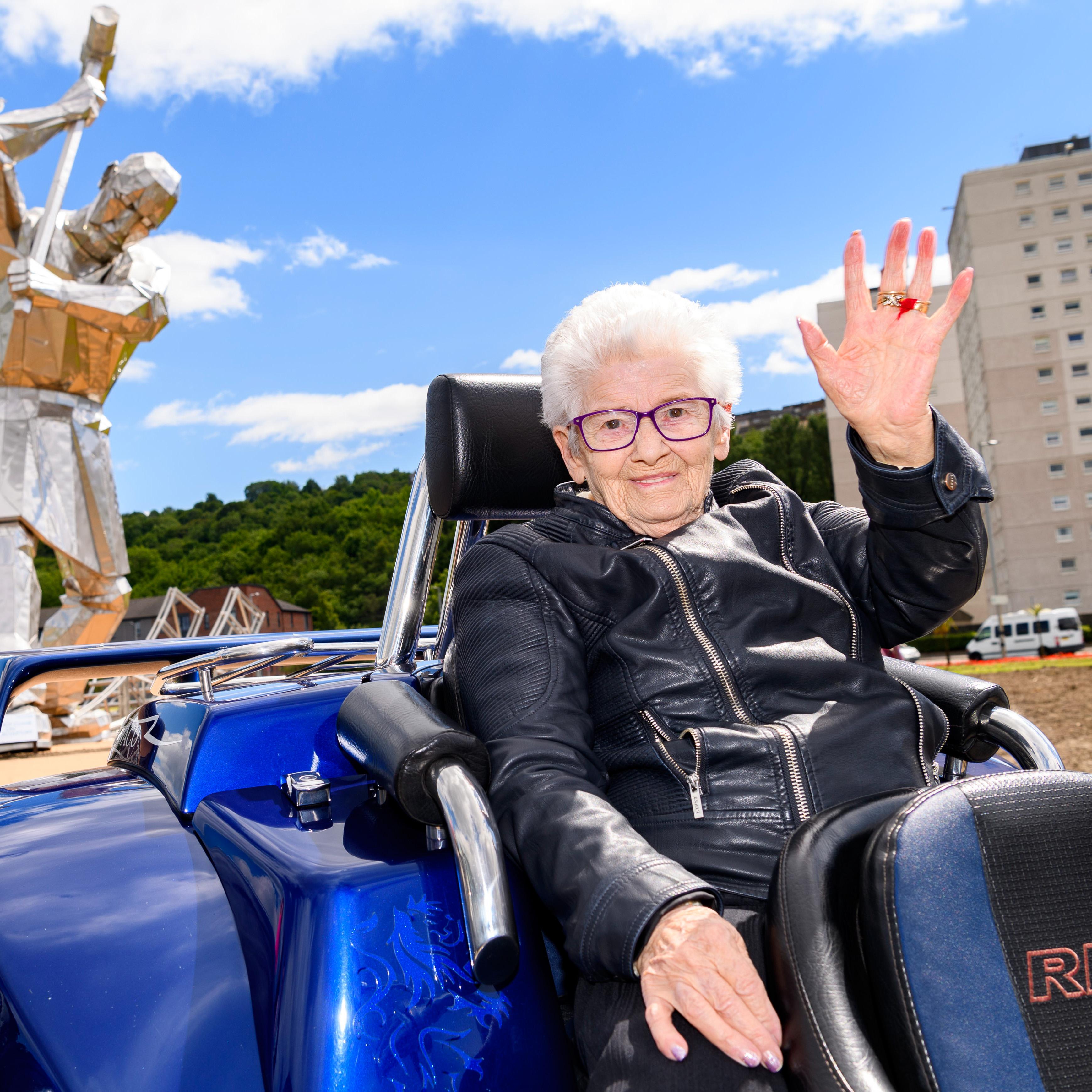 Margaret Sneddon on motorbike waving to camera